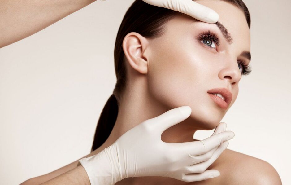 The cosmetologist examines the skin of the face before rejuvenation